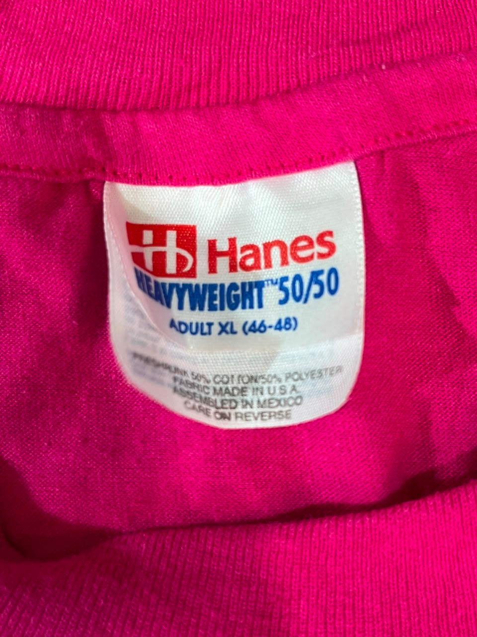 Close-up of a pink garment's interior neck label, showing the brand name Hanes and size information.