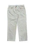A pair of light beige or off-white denim jeans on the white background