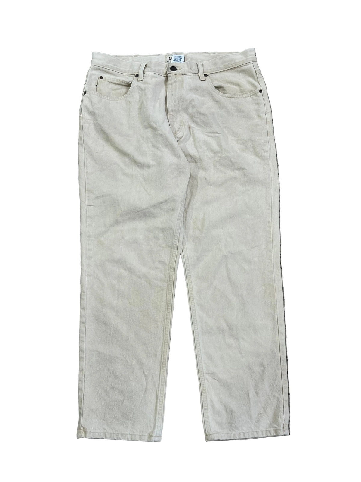 A pair of light beige or off-white denim jeans on the white background