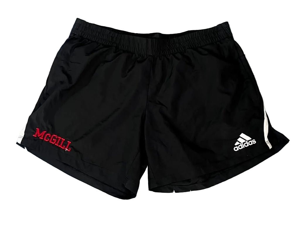 Black athletic shorts with an elastic waistband, featuring a red 'MCGILL' logo on the left side and a white Adidas logo on the right side,.
