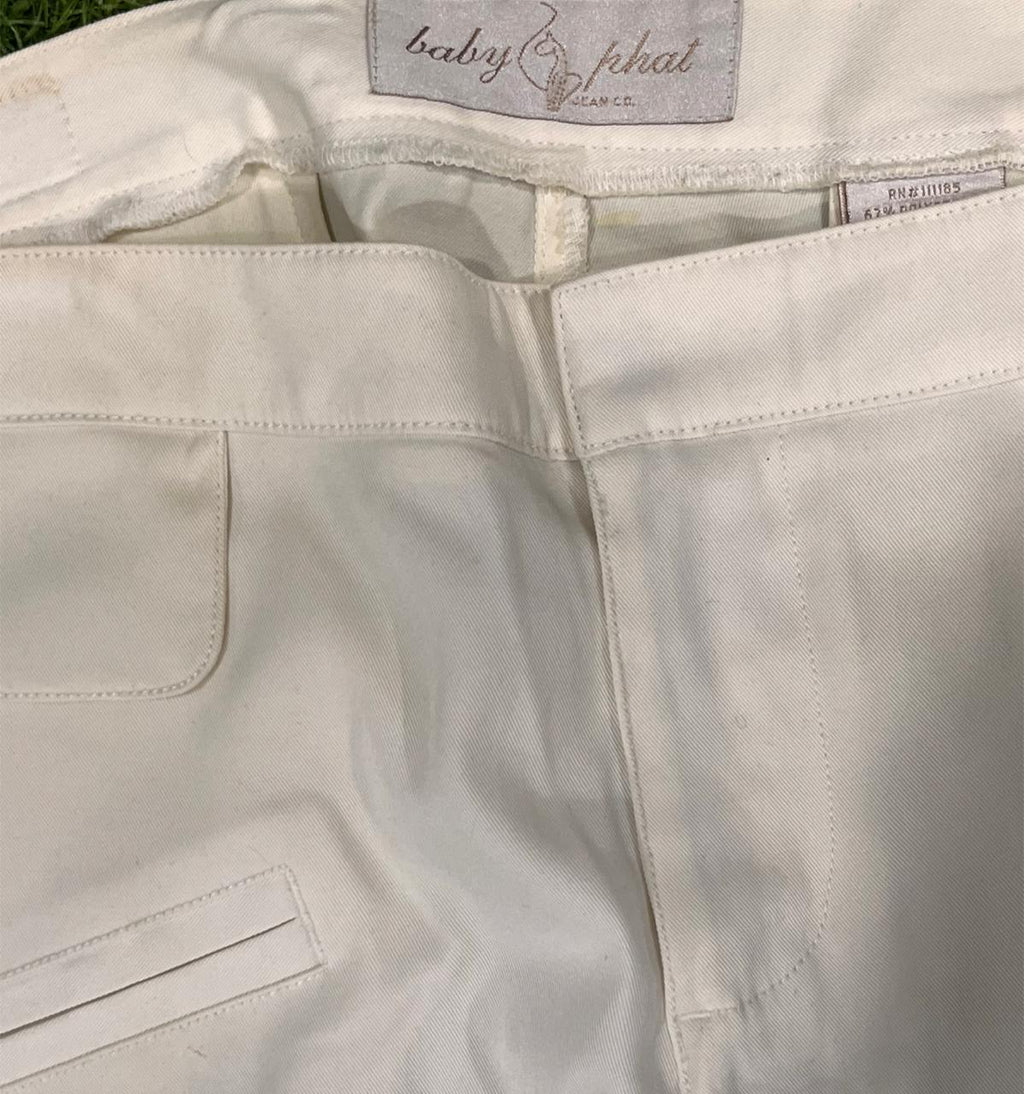 Close-up of light-colored pants with a brand label on the waistband.