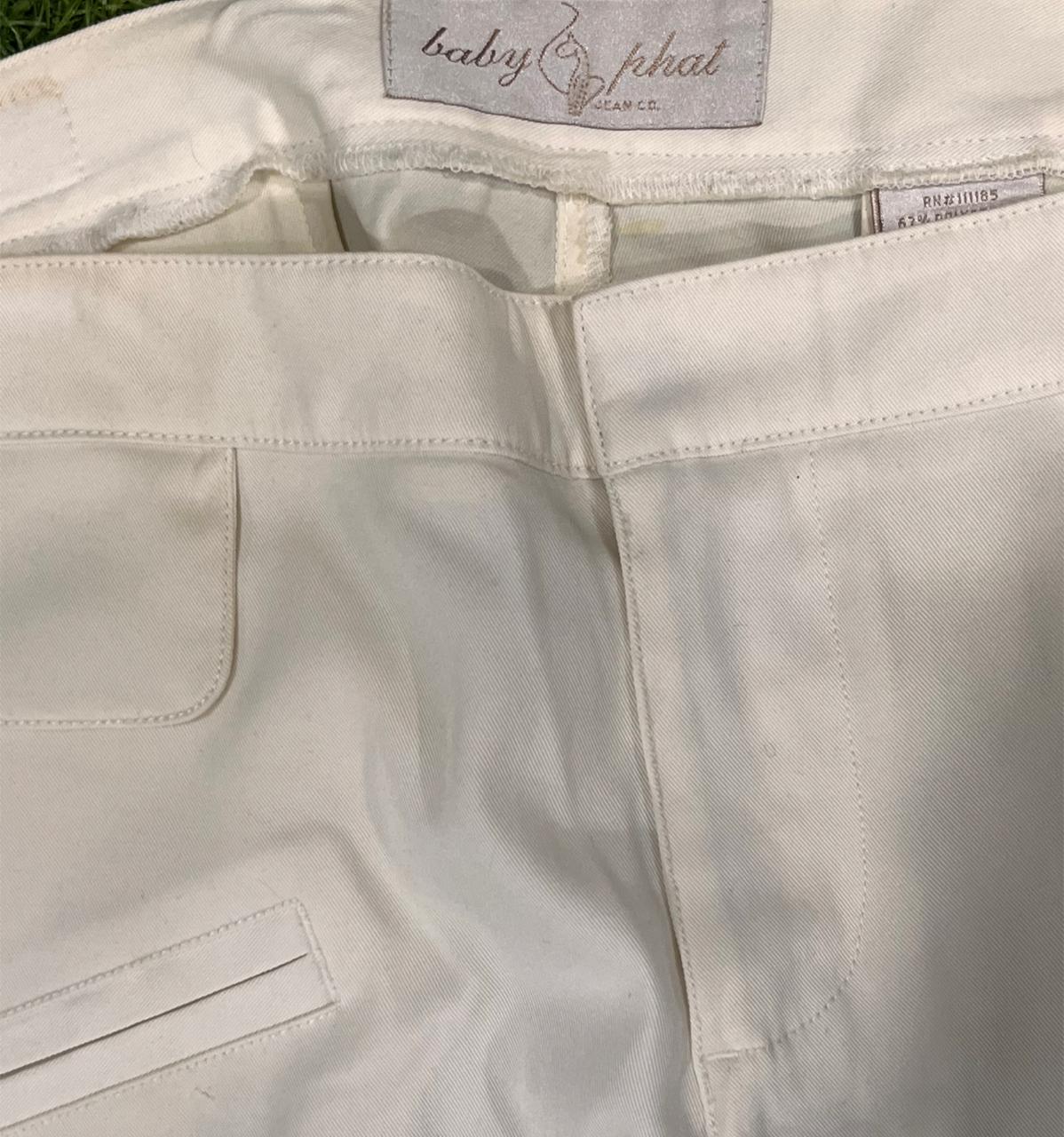 Close-up of light-colored pants with a brand label on the waistband.