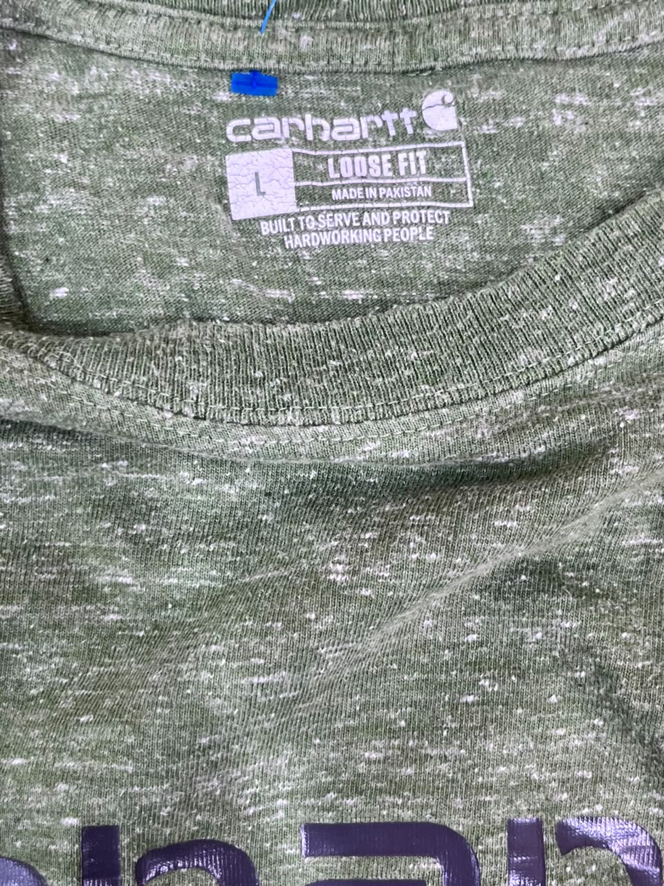 Close-up of a Carhartt green heathered t-shirt showing the inner neck label with size information and the Carhartt logo.