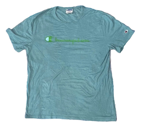 A Champion short-sleeve t-shirt in a muted teal-green color The shirt features a green Champion logo and script across the chest, and the signature C logo on the left sleeve.