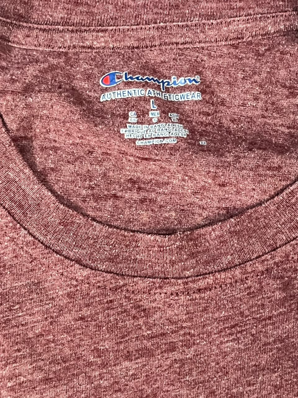 Close-up of a heathered reddish-brown Champion t-shirt collar showing the Champion brand tag.