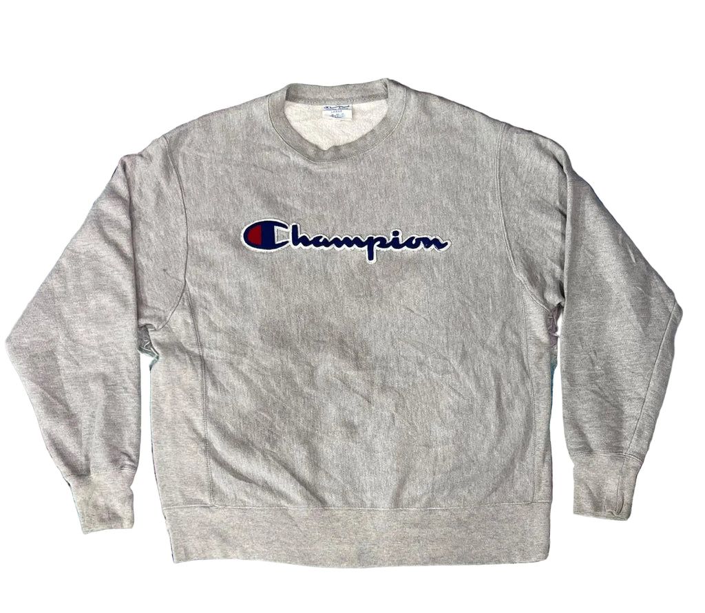 A heather gray crewneck sweatshirt with the embroidered Champion logo on the chest
