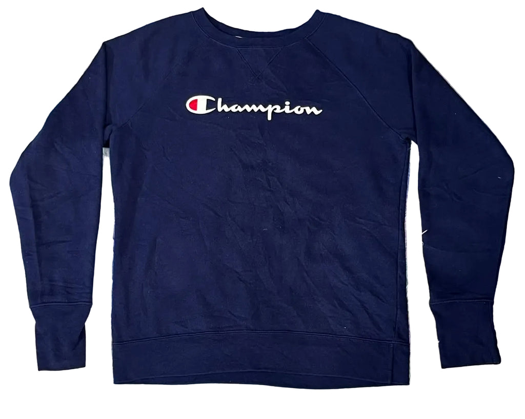 A navy blue Champion crewneck sweatshirt with the brand's signature 'C' logo and 'Champion' script across the chest, laid flat on a colorful, textured faux fur surface.