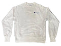 A white Champion crewneck sweatshirt with the brand's signature 'C' logo embroidered in navy blue on the left chest, laid flat on a textured blue and purple shag rug.