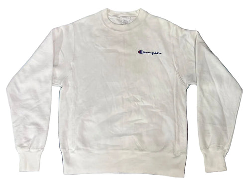 A white Champion crewneck sweatshirt with the brand's signature 'C' logo embroidered in navy blue on the left chest, laid flat on a textured blue and purple shag rug.