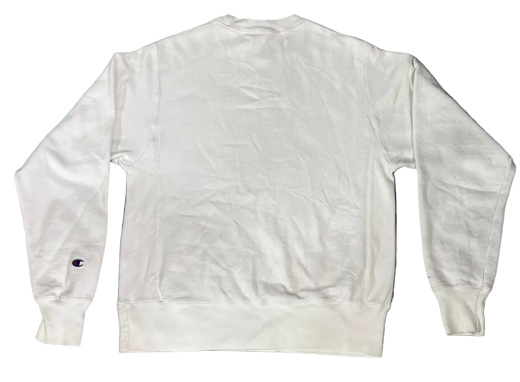 A white long-sleeve crewneck sweatshirt multicolored blue and purple rug. A small Champion 'C' logo is visible on the left sleeve cuff.