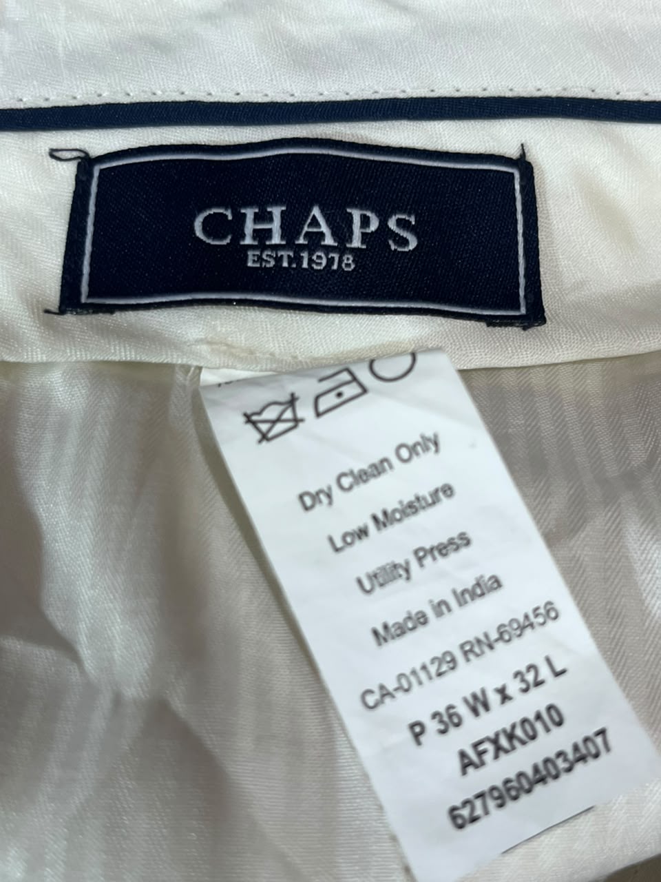 Close-up of a CHAPS garment label sewn onto white fabric, with a white care instruction tag below it.