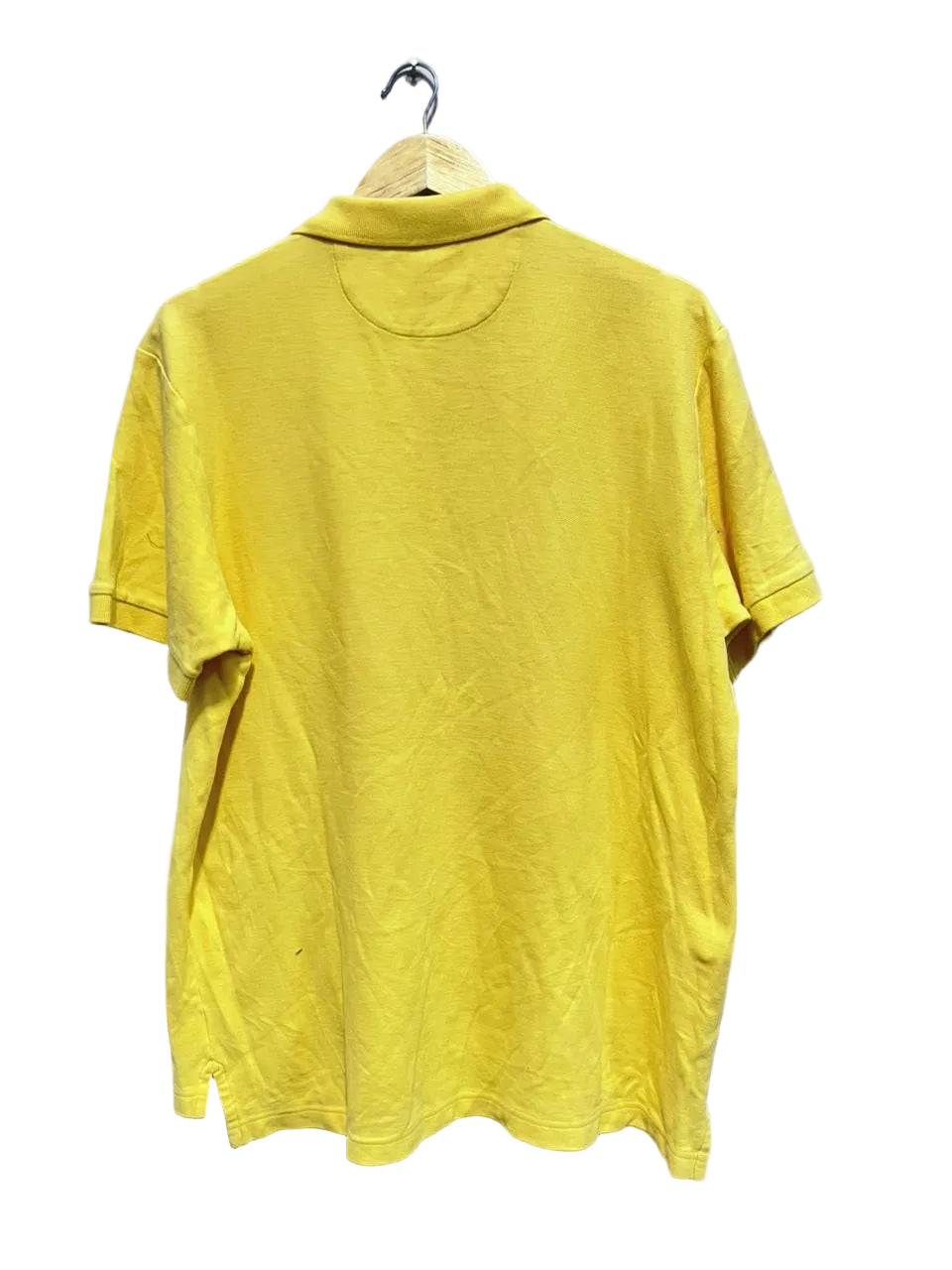 Chaps yellow polo shirt on a hanger against a white wall