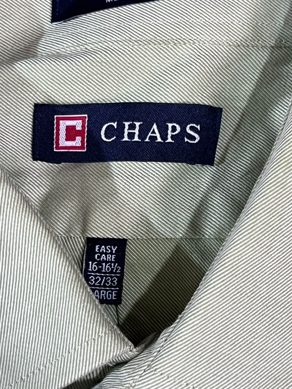 Close-up of a Chaps neck label on a light gray ribbed fabric garment, with a size tag reading 16-16 1/2, 32/33, and LARGE.