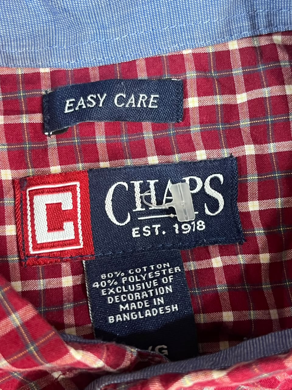 Close-up of a red and beige plaid shirt lining with a navy blue CHAPS brand label, an 'EASY CARE' label, and a red-and-white check patch.