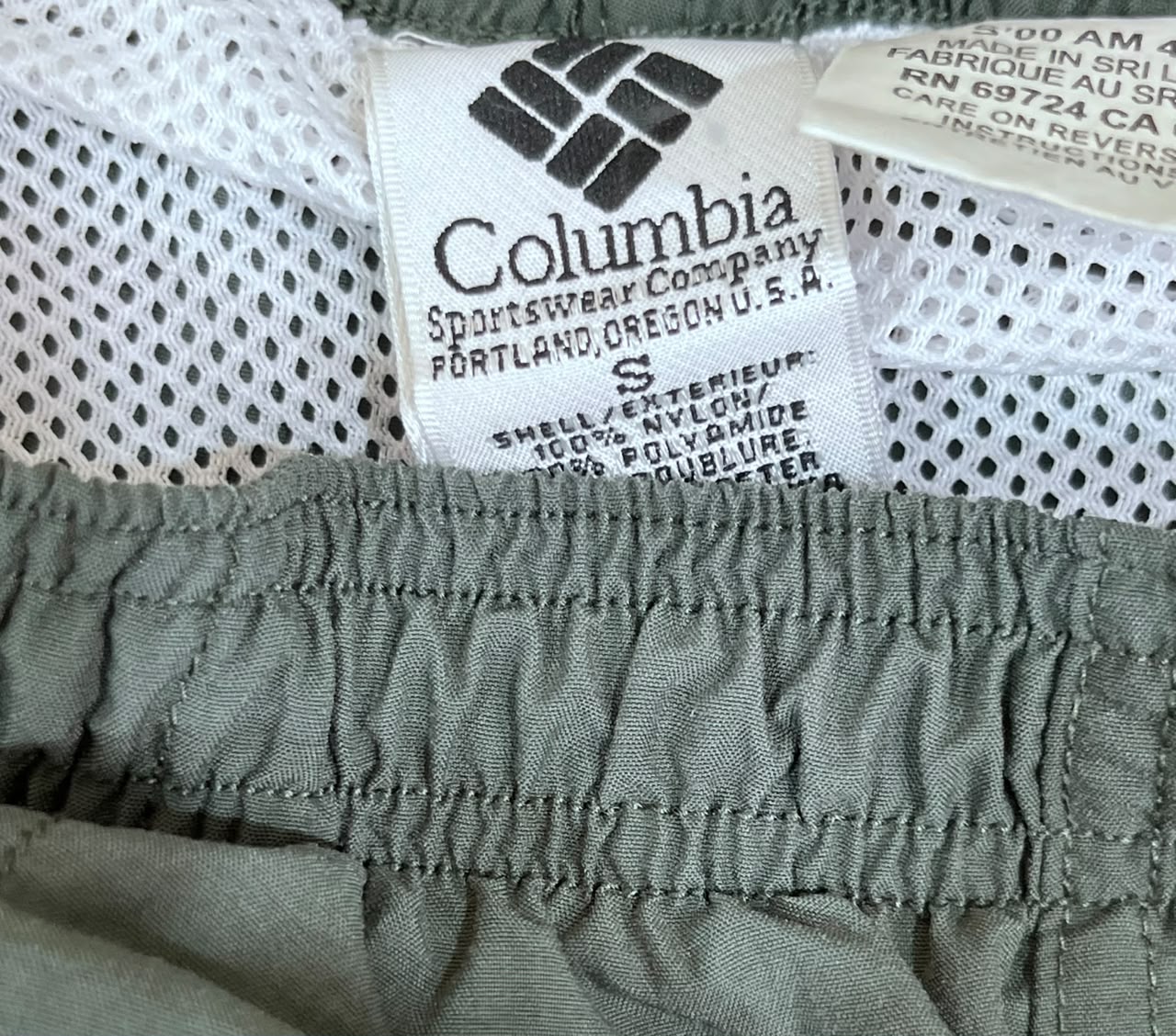 Close-up of a Columbia athletic garment showing the brand label, white mesh lining, and an olive green elasticized fabric section.