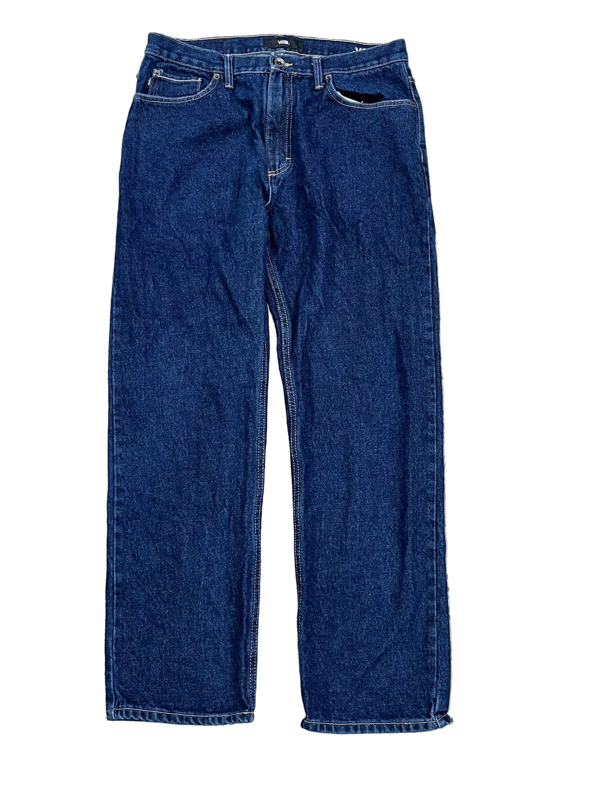 A pair of dark blue denim jeans laid flat on a speckled gray and white terrazzo floor.