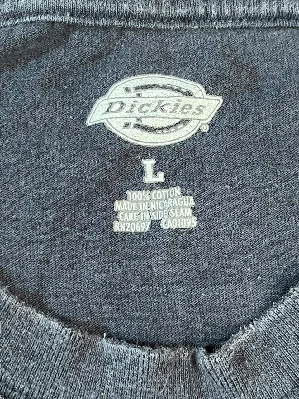 Close-up of a dark gray Dickies t-shirt showing the inner neck label with the white embroidered Dickies logo and size information.