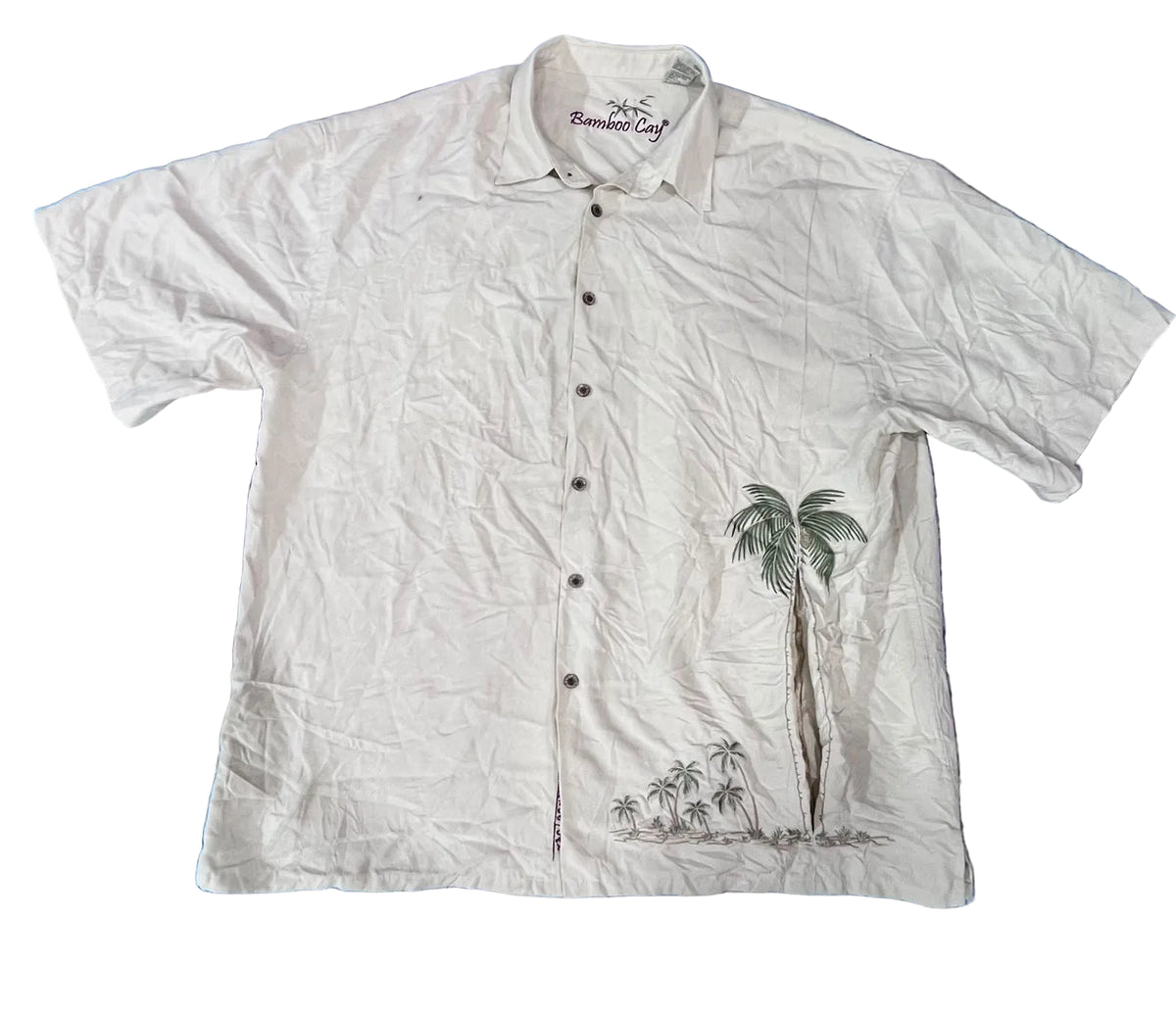 A white short-sleeve button-up shirt with a palm tree graphic on the lower right side The brand 'Romantic Cafe' is printed inside the collar.