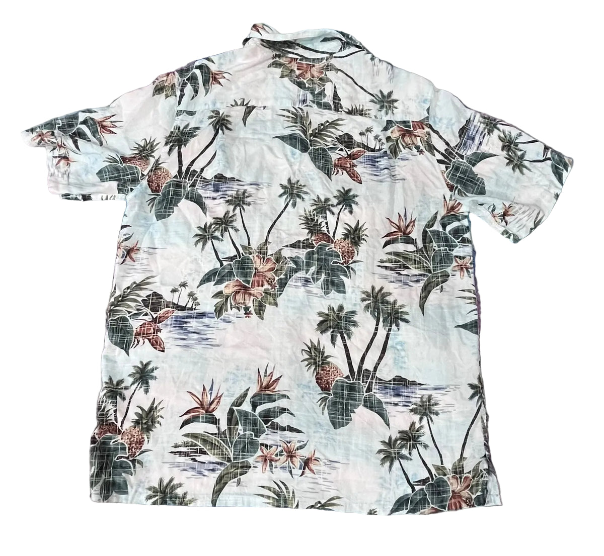 A short-sleeve Hawaiian-style camp shirt The shirt features a tropical print with palm trees, hibiscus flowers, and blue water motifs on a white background.