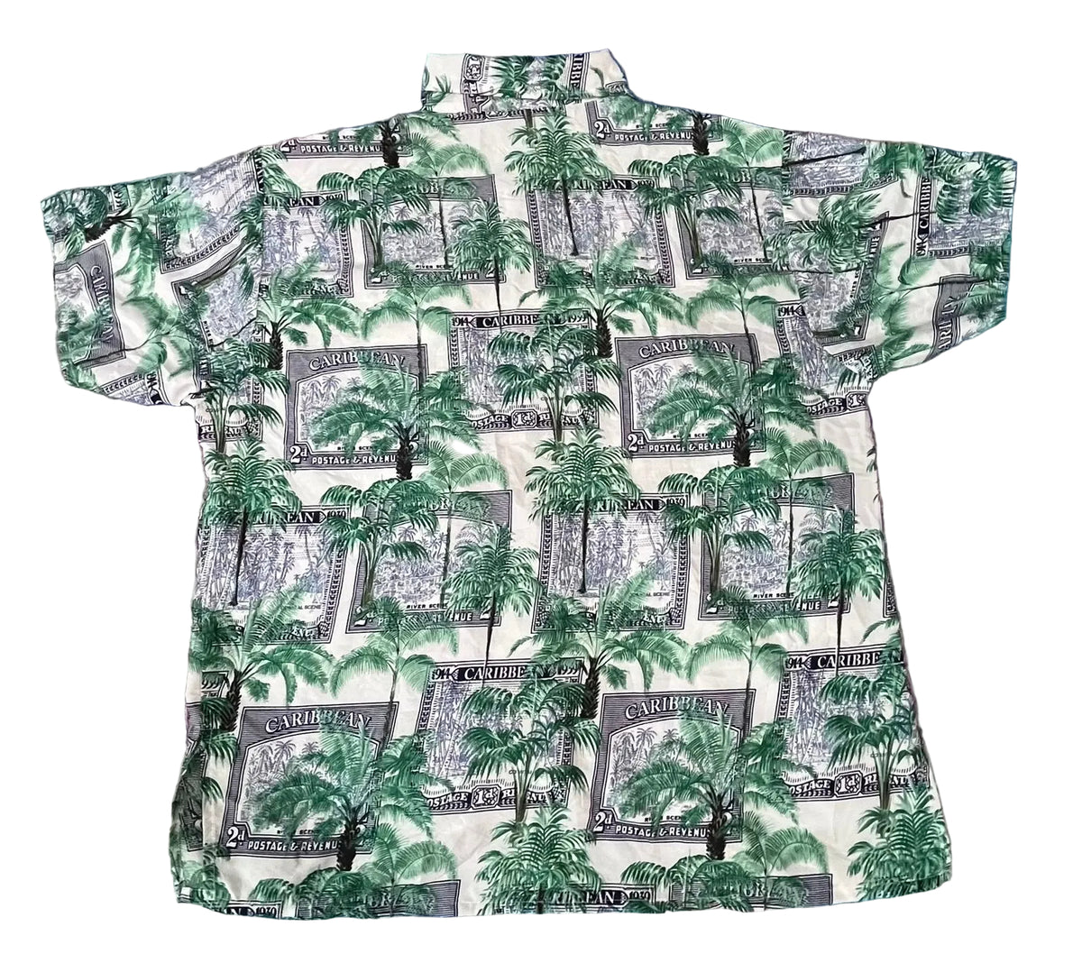 A short-sleeve button-up shirt. The shirt features an all-over print of green palm trees and gray-and-white dollar bill designs with the words 'CARIBBEY' and 'ONE DOLL'.