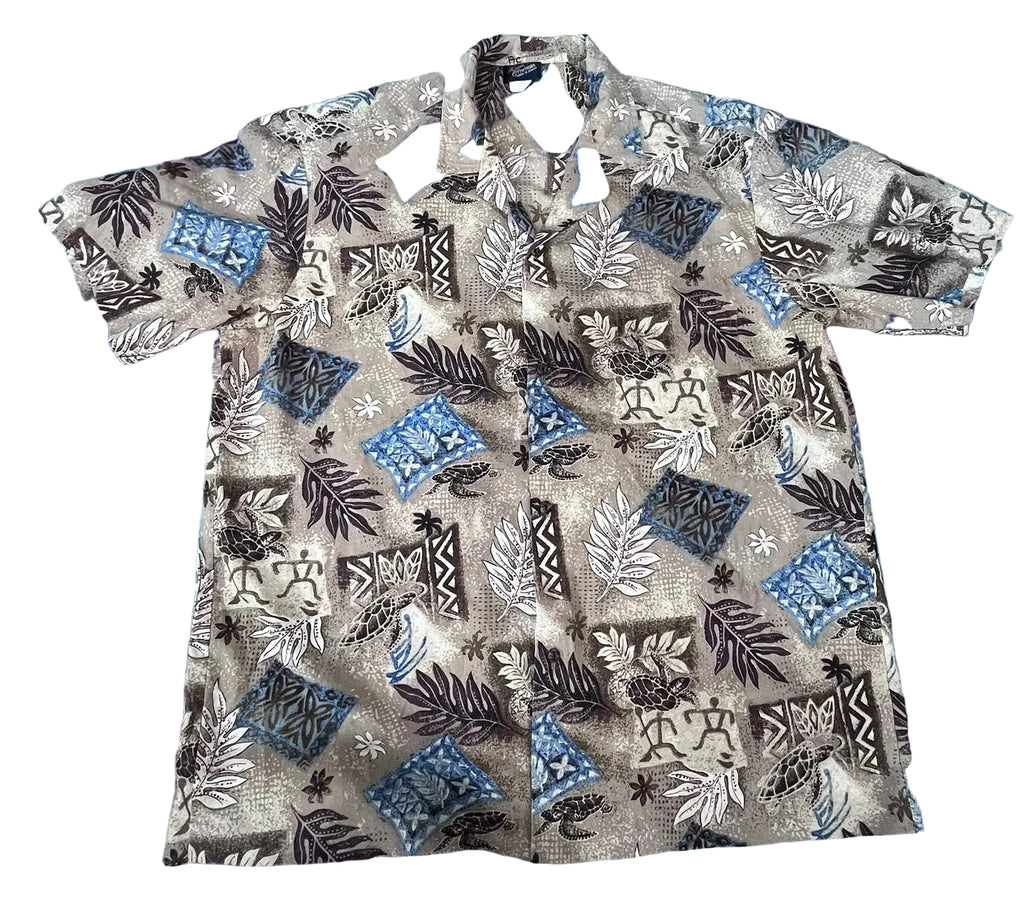 A short-sleeve button-up camp shirt with a tropical and Polynesian-inspired pattern,. The shirt features a beige base with black, white, and blue motifs including palm leaves, geometric patterns, and stars.