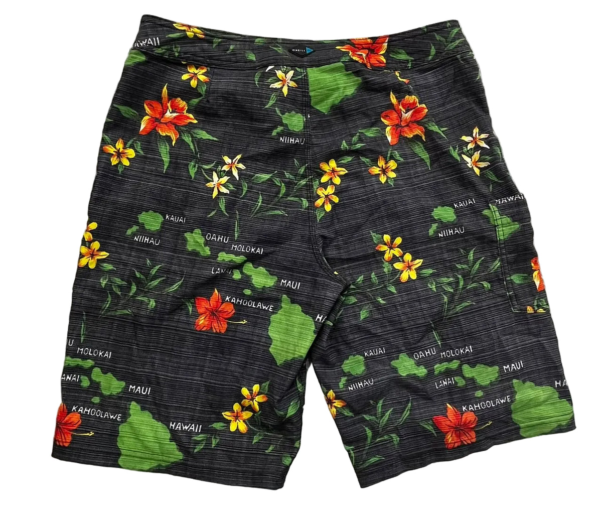 Black Hawaiian-themed swim trunks with a floral print of red and yellow flowers, green leaves, and white text spelling out 'MAUI', 'HAWAII', 'KUMU', 'OLAKAWA', and 'MOLOKAWA'.
