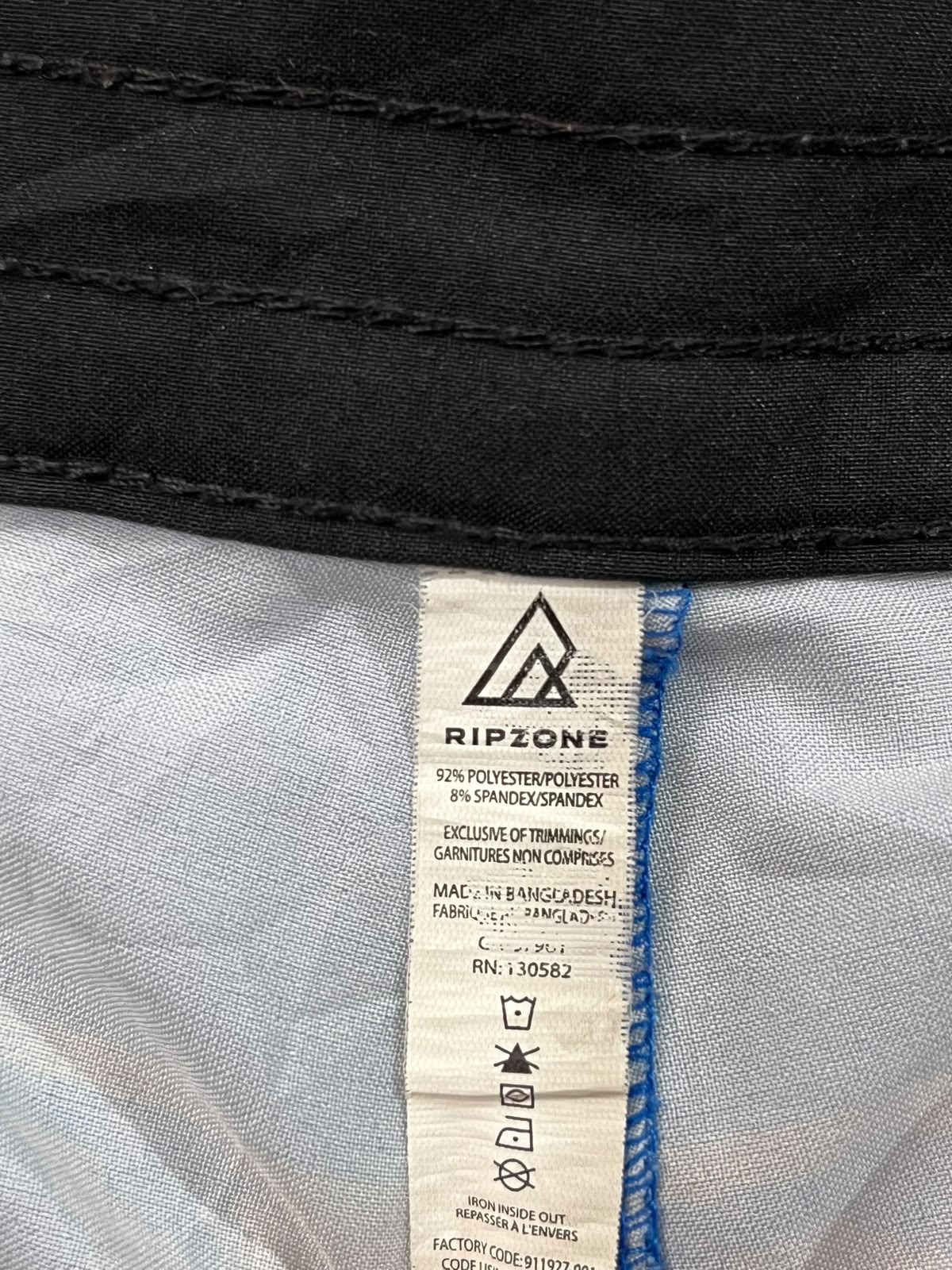Close-up of a Ripzone garment label sewn inside the collar of a black and white jacket, showing the brand name and care instructions.