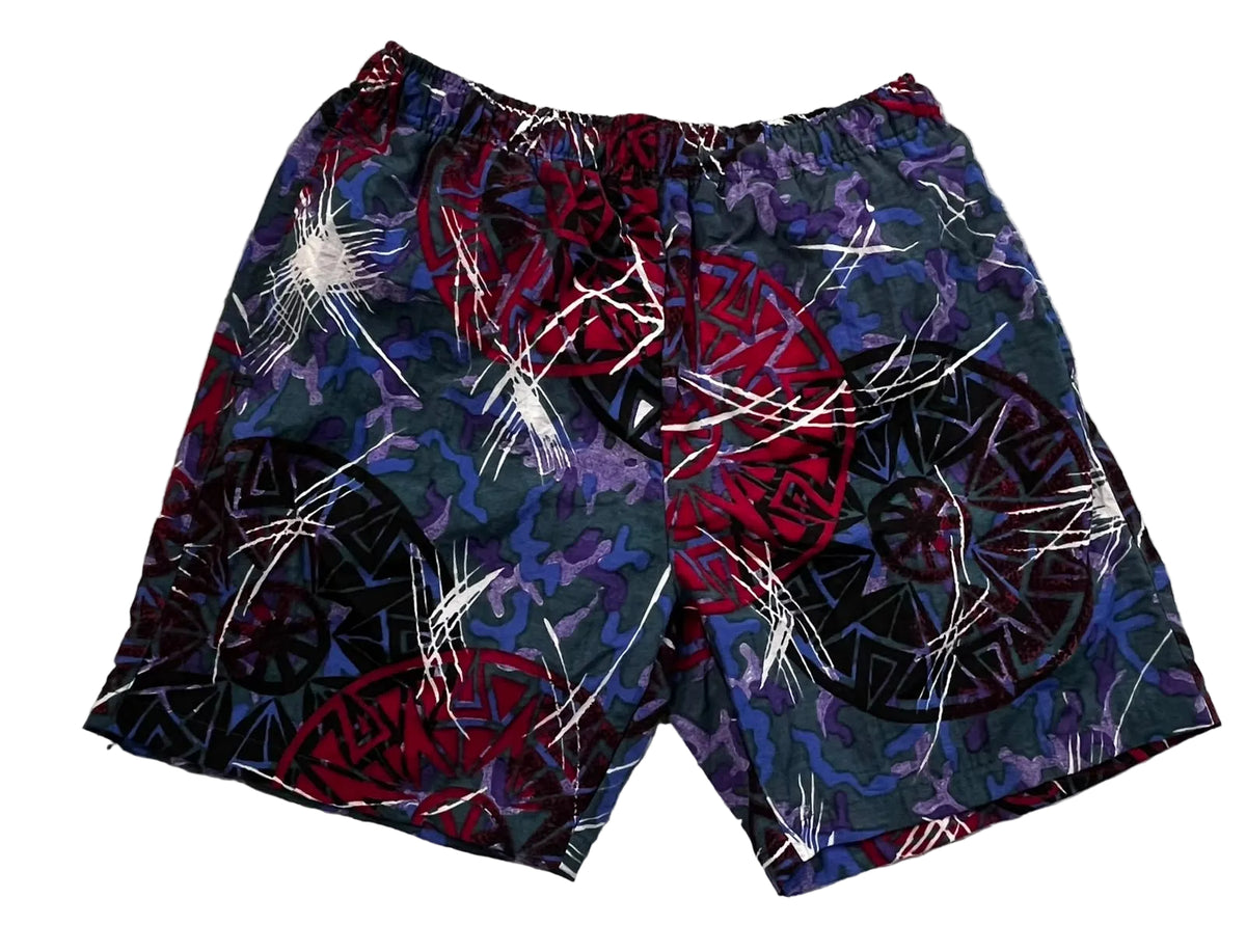 A pair of men's shorts featuring a complex abstract pattern with red, purple, black, and white elements,