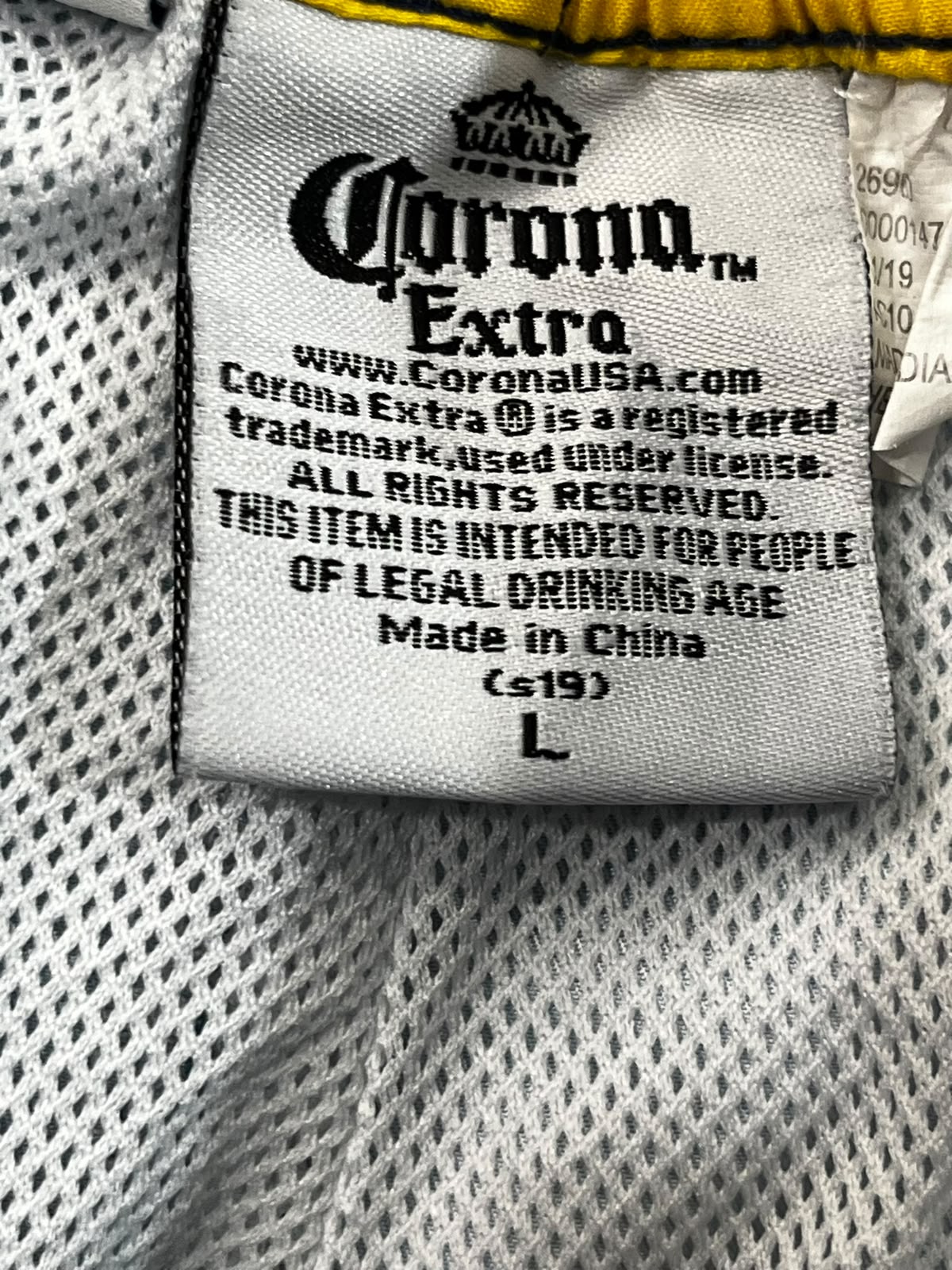 Close-up of a sewn-in product label reading Corona Extra, with visible mesh fabric and interior lining around it.