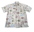 A short-sleeve button-up camp shirt with a tropical print featuring palm trees, beach umbrellas, and geometric tiles in muted green, blue, and brown on a cream background, 