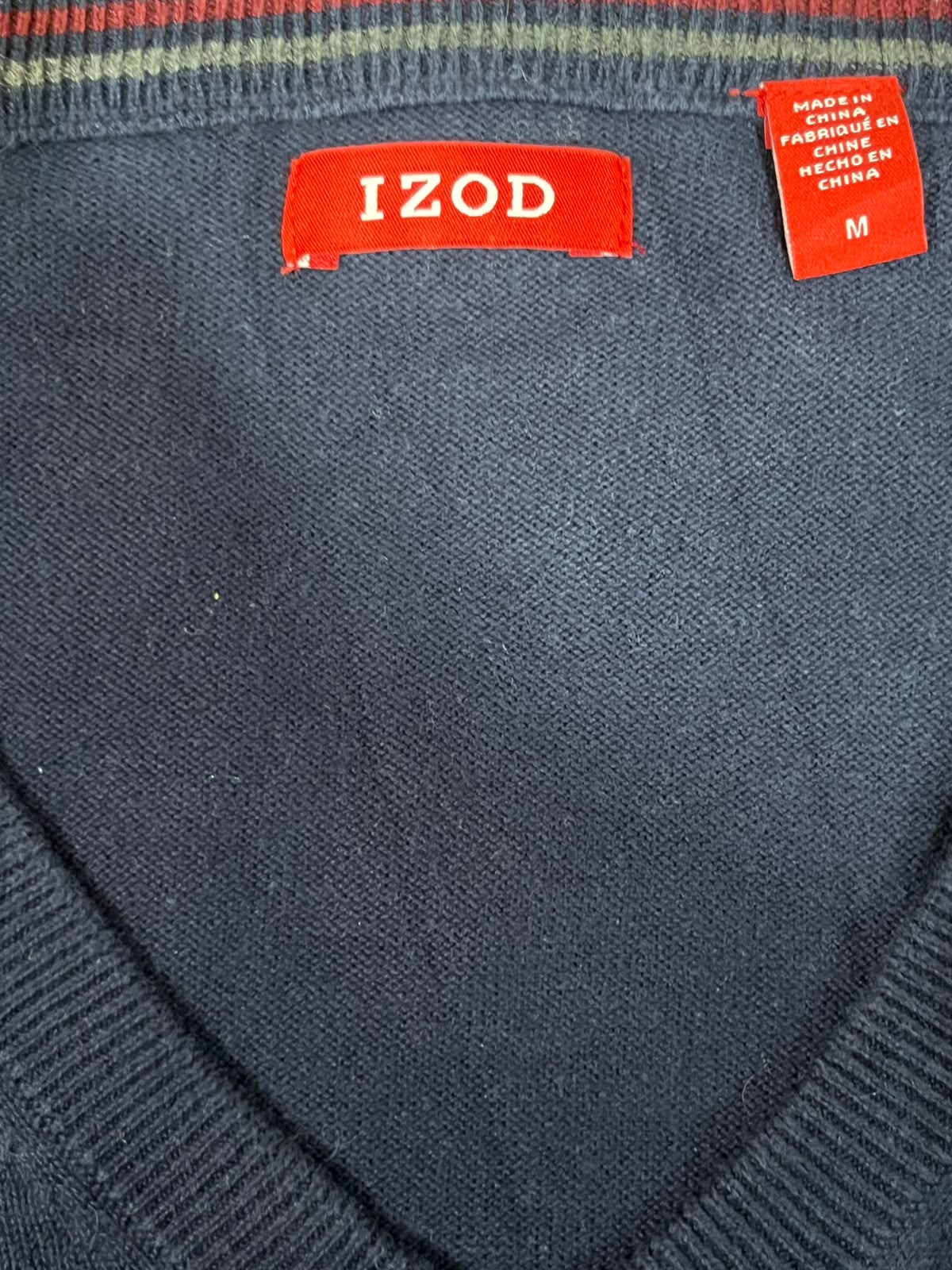 Close-up of a navy knit sweater or v-neck top showing the inside neckline with a redIZOD label and a red size tag reading M.