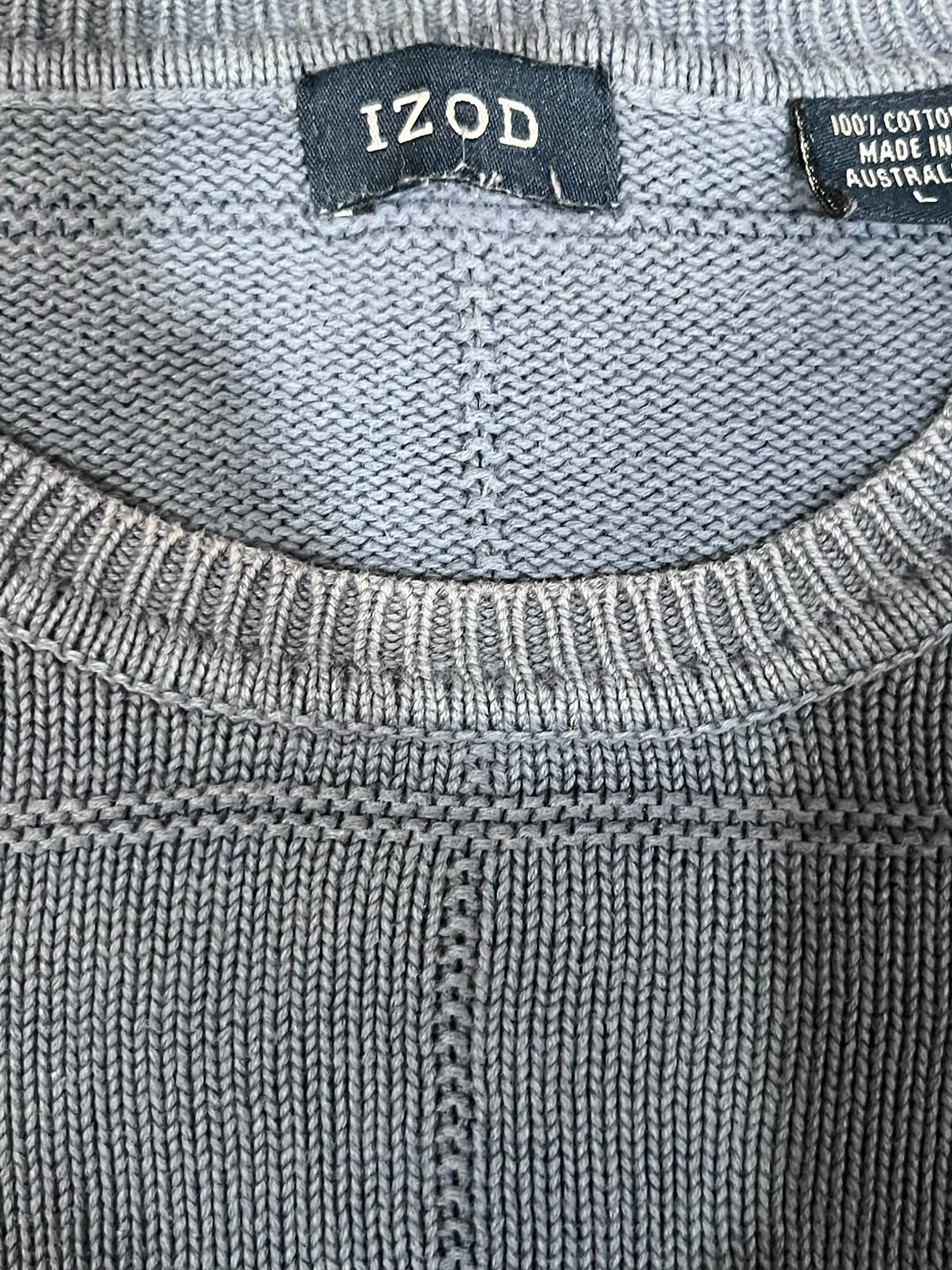 Close-up of a gray knit crewneck sweater showing the ribbed collar and an Izod brand label.