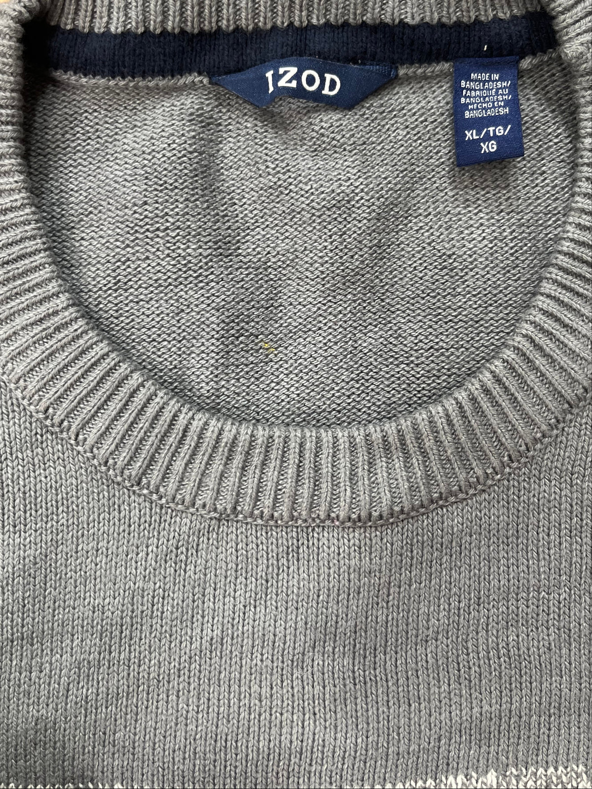 Close-up of a gray ribbed knit crewneck sweater showing the inside neck with a navy blue Izod brand label and a size tag.