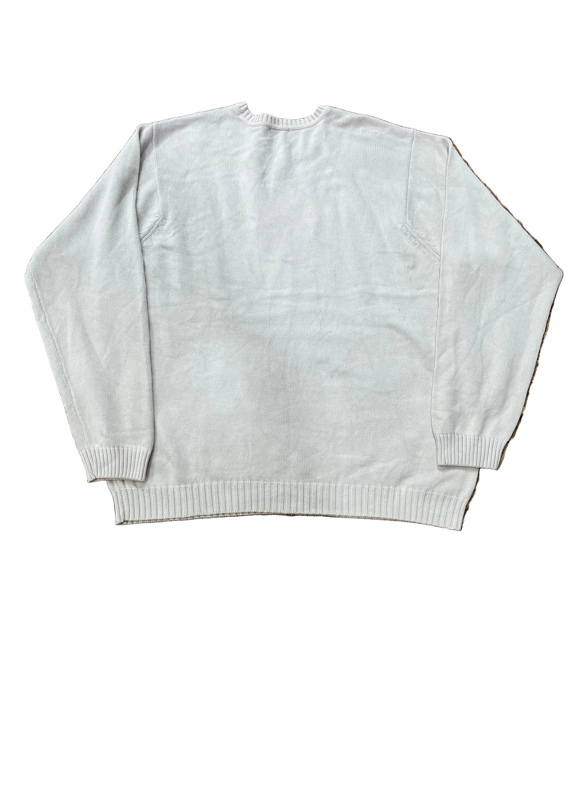 A white long-sleeve knit sweater  with bare feet visible at the bottom corners.