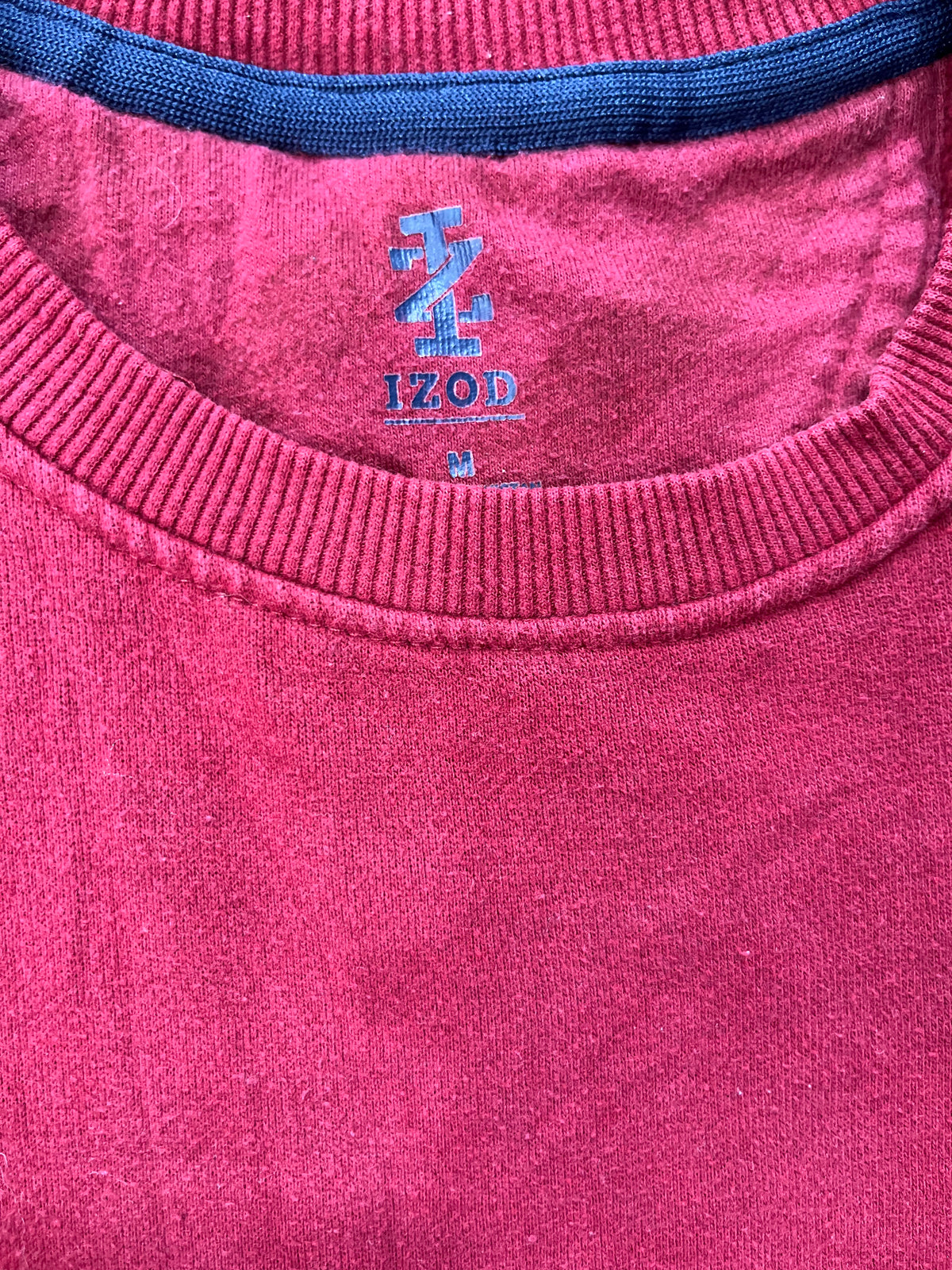 Close-up of a pink knit crewneck sweater with a blue ribbed collar trim and a blue embroidered logo reading '120D' inside the neckline.