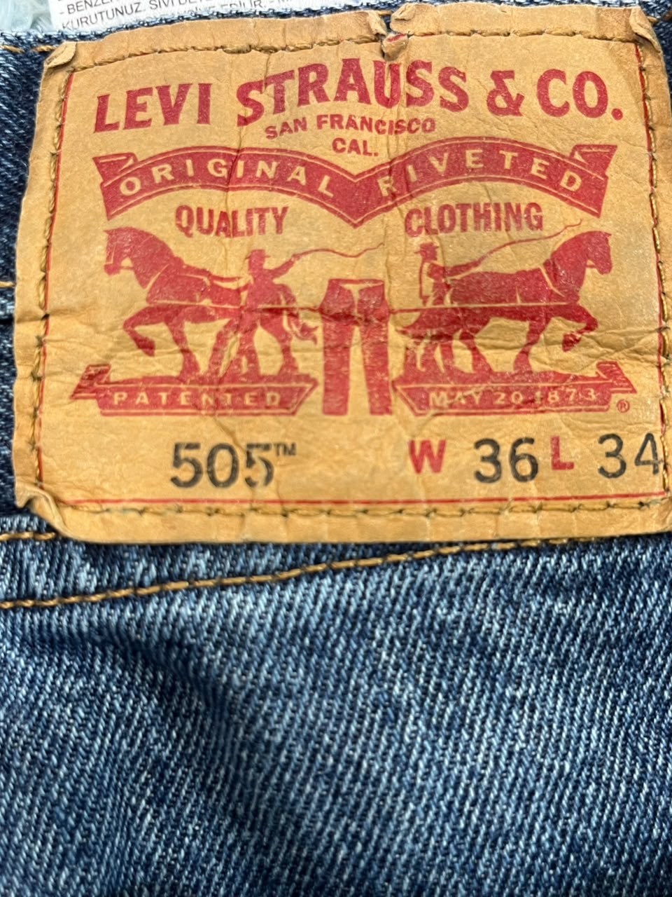 Close-up of a vintage Levi's 505 waistband label sewn onto blue denim jeans, showing the red Levi's branding and size markings W 36 L 34.