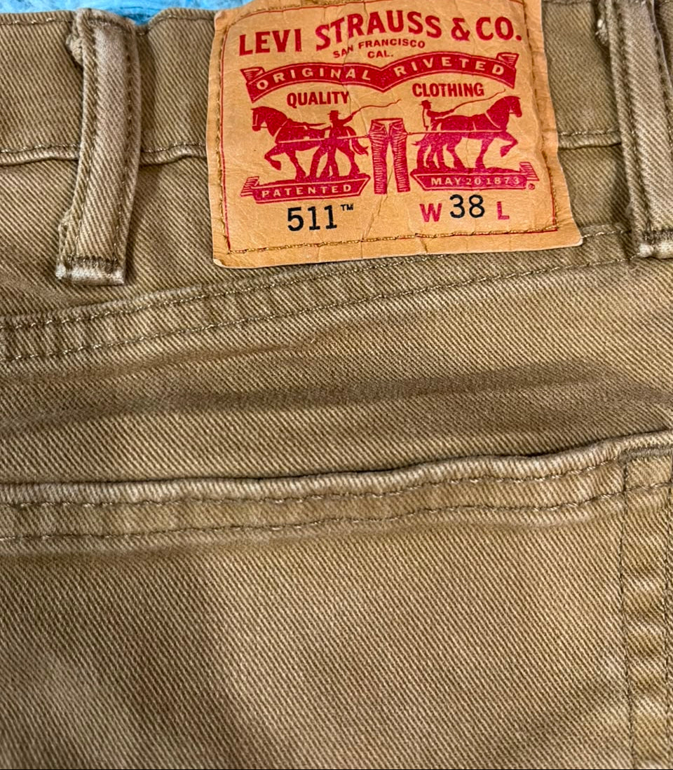 Close-up of the waistband of tan Levi's jeans showing the red and tan leather brand patch.