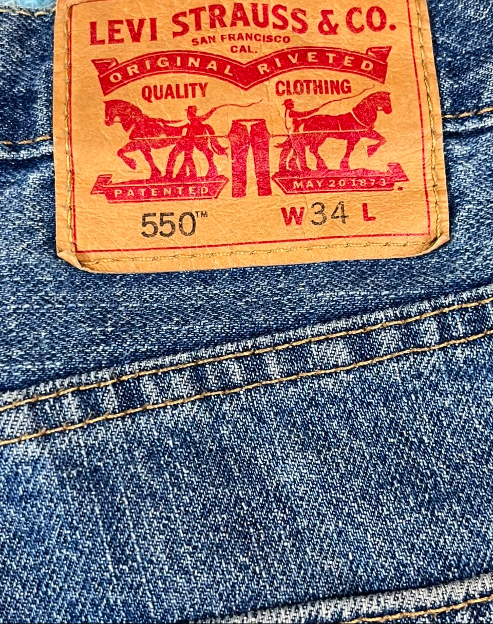 Close-up of a blue denim jeans back pocket showing the iconic tan leather Levi's patch with red printed branding and size information.