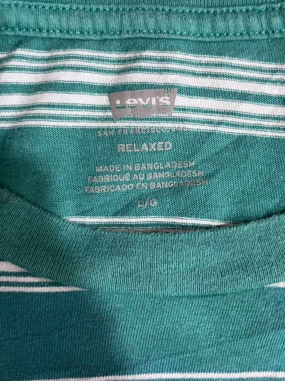 Close-up of a Levi's relaxed-fit striped t-shirt collar, showing the brand label and green and white horizontal stripes.