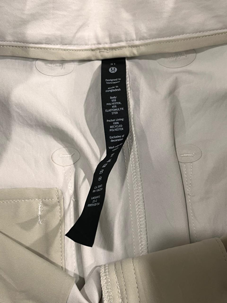 Close-up of a beige jacket with a brand tag on a light gray background