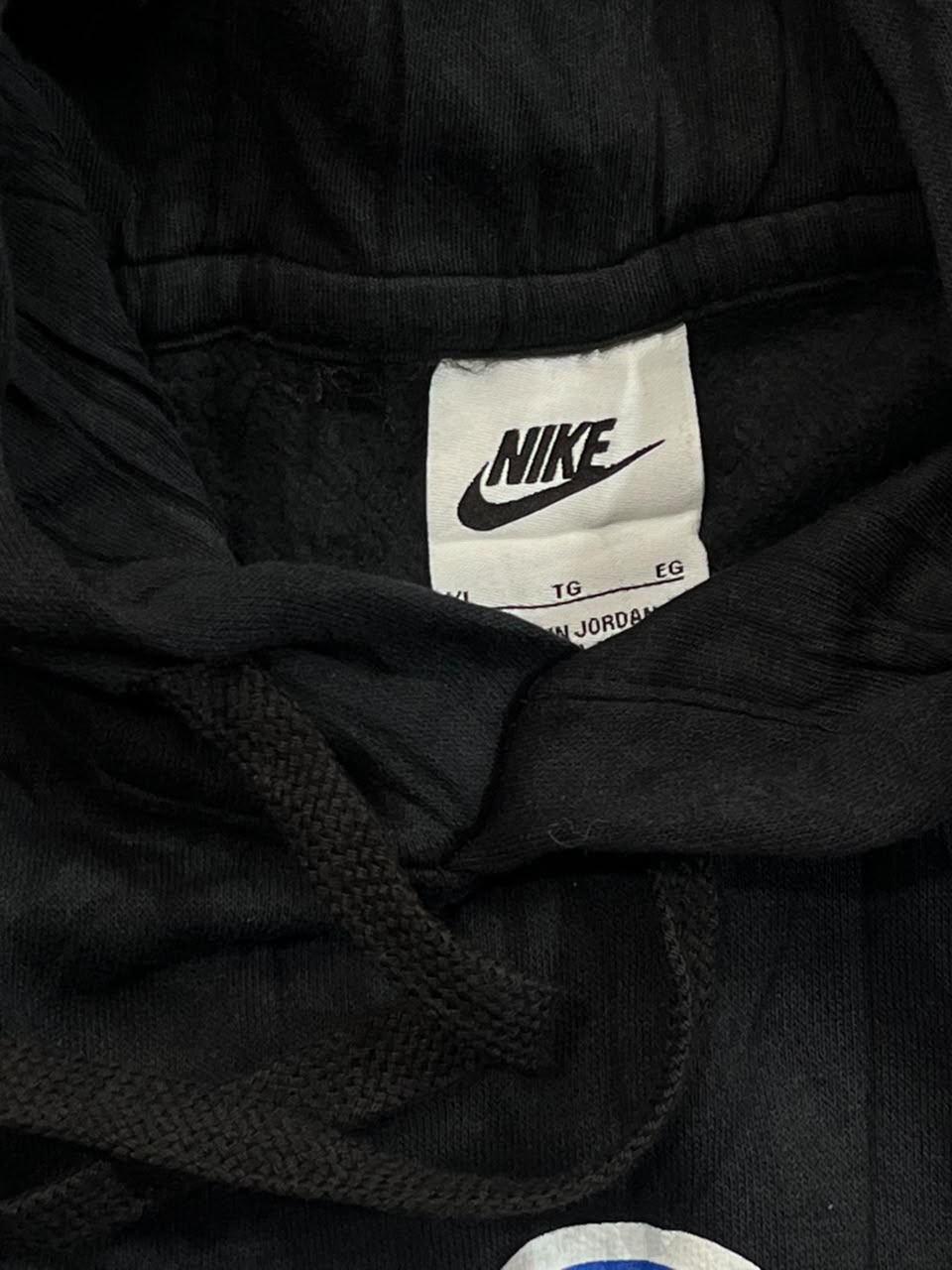 Close-up of a black Nike garment showing the interior neck label with the Nike logo and drawstring cord.