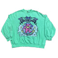 A mint green long-sleeve t-shirt with a colorful Grateful Dead 'The Moon Is Down' graphic, . A person's foot is visible on the left edge of the frame.