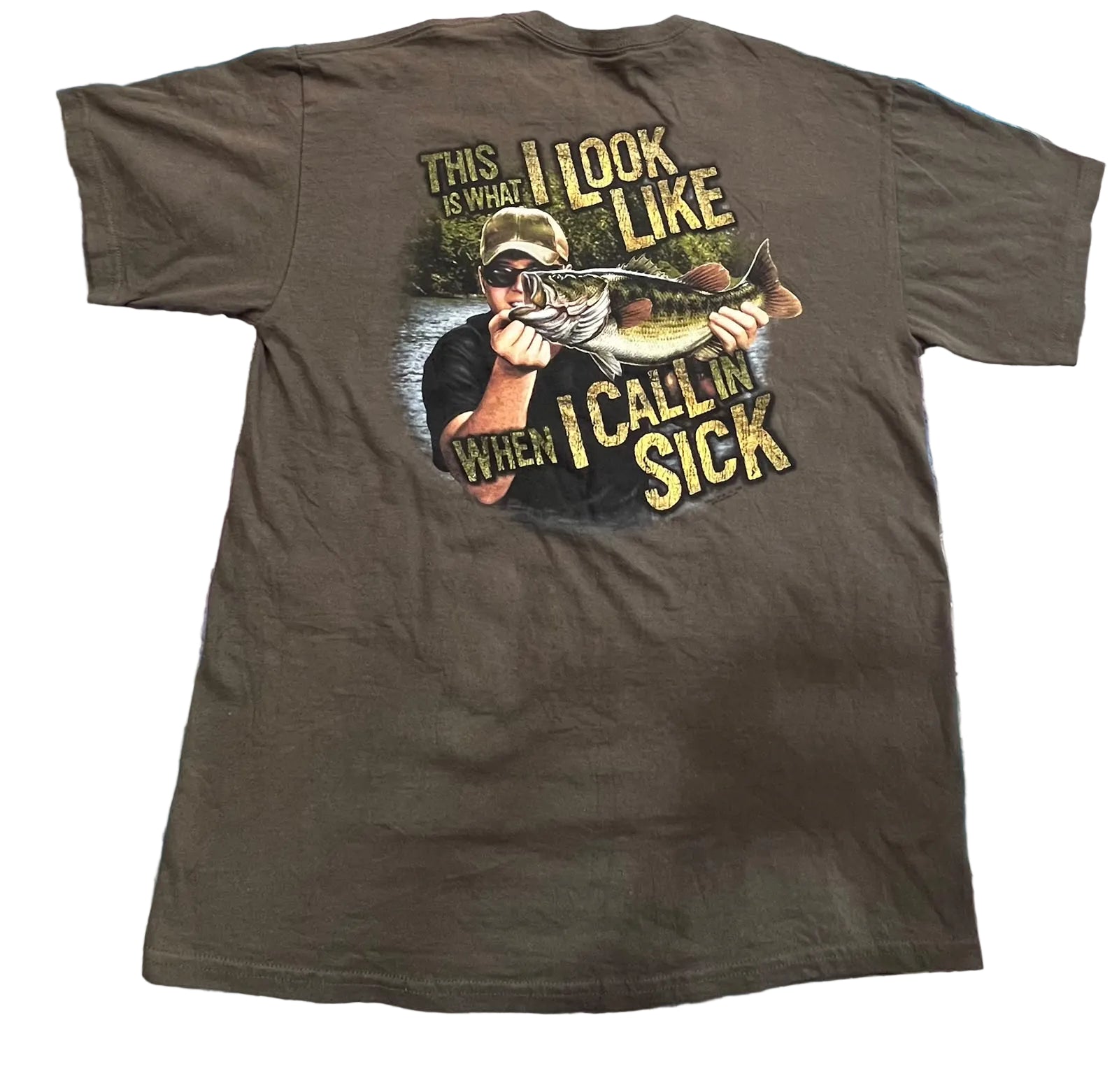 A dark brown short-sleeve t-shirtThe back of the shirt features a large graphic print of a man holding a fish with the text 'THIS IS WHAT I LOOK LIKE WHEN I CALL IN SICK' in yellow lettering.