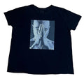 A black short-sleeve t-shirt  featuring a square graphic print of a person with hands over their face in a blue-toned photo.