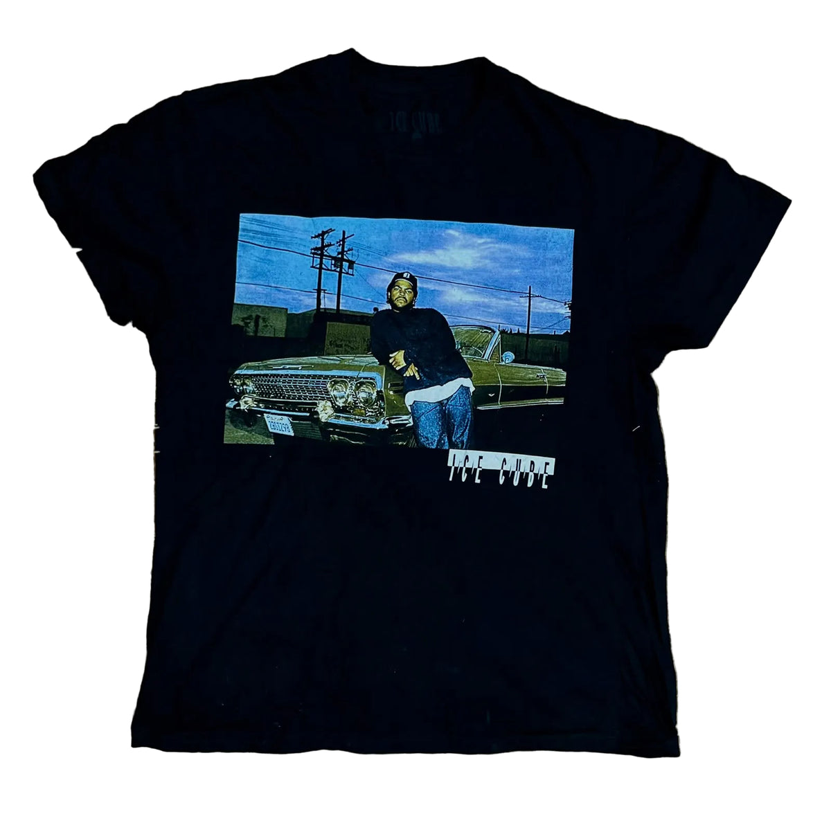 A black short-sleeve graphic t-shirt  The shirt features a rectangular printed graphic on the front showing Tupac Shakur leaning on a green convertible car under a blue sky.