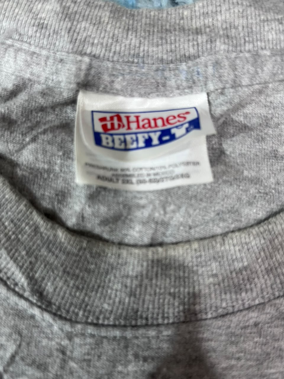 Close-up of a gray heather crewneck t-shirt showing the white Hanes Beefy-T brand neck label.