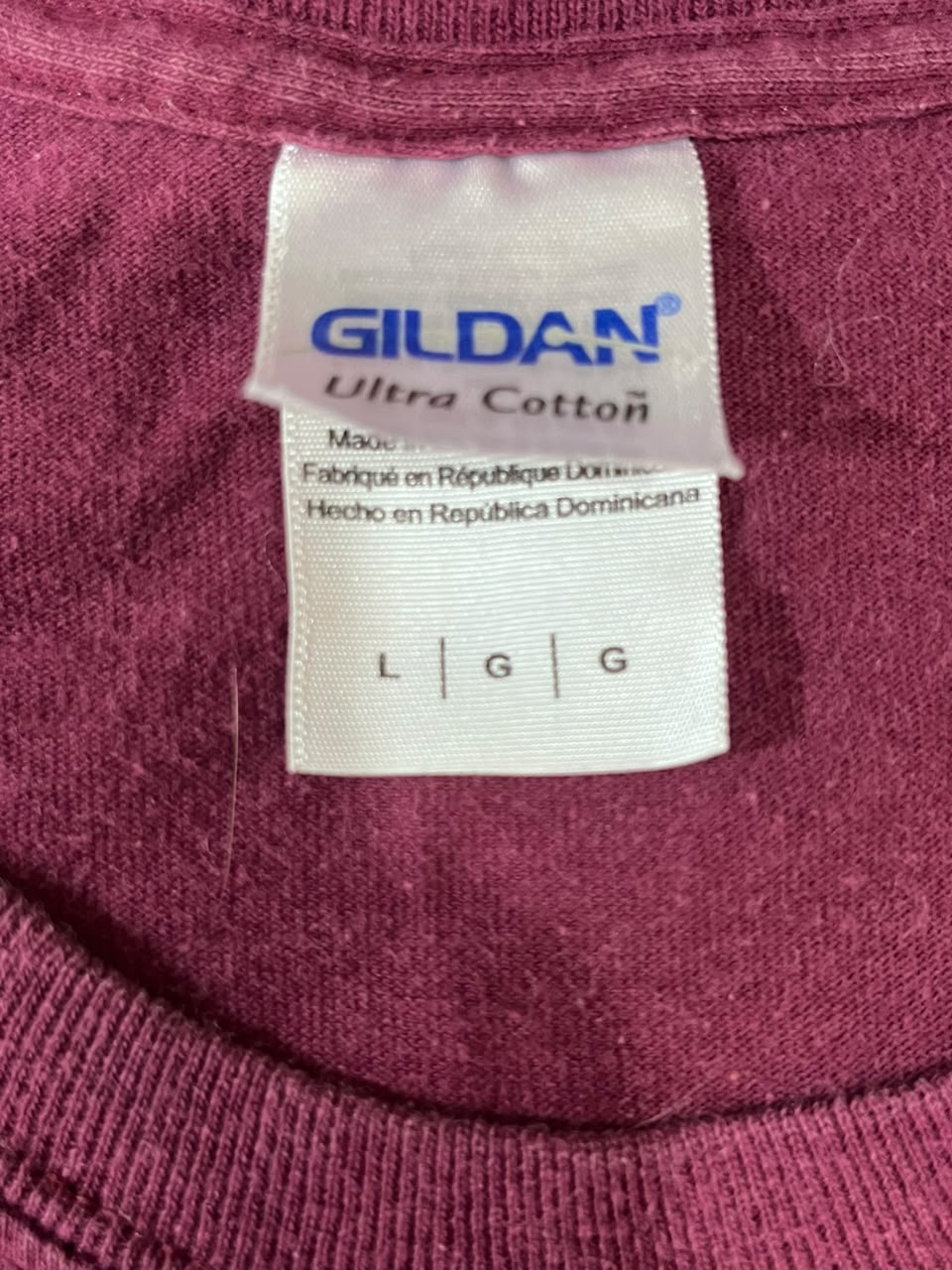 Close-up of a Gildan Ultra Cotton garment label sewn inside the collar of a burgundy knit shirt.