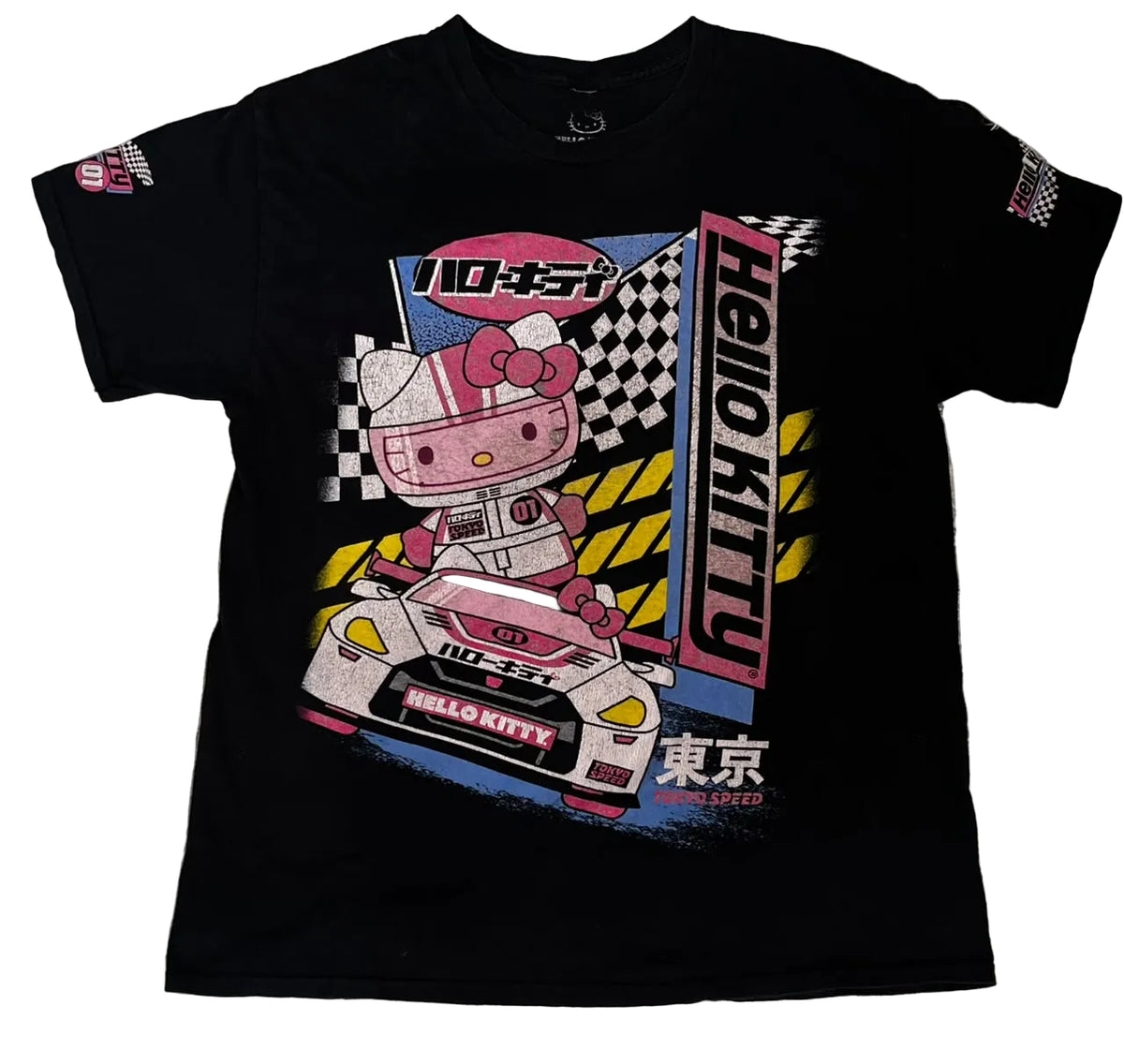 A black short-sleeve graphic T-shirt . The shirt features a large Hello Kitty racing design on the front with a pink character in a race car, checkered flags, and vertical 'HELLO KITTY' text.