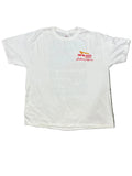 A white short-sleeve t-shirt with a red and yellow 'Inn-Out Steakhouse & Bar' logo on the left chest, laid flat on a green shag rug with bare feet visible at the bottom.