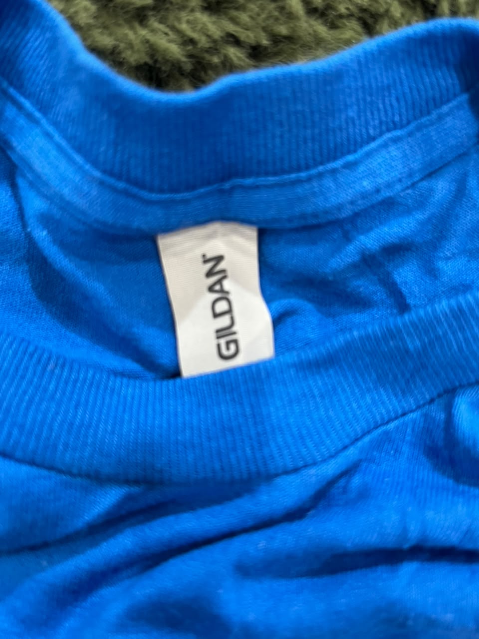 Close-up of a bright blue ribbed knit garment with a white Gildan brand tag visible at the collar.